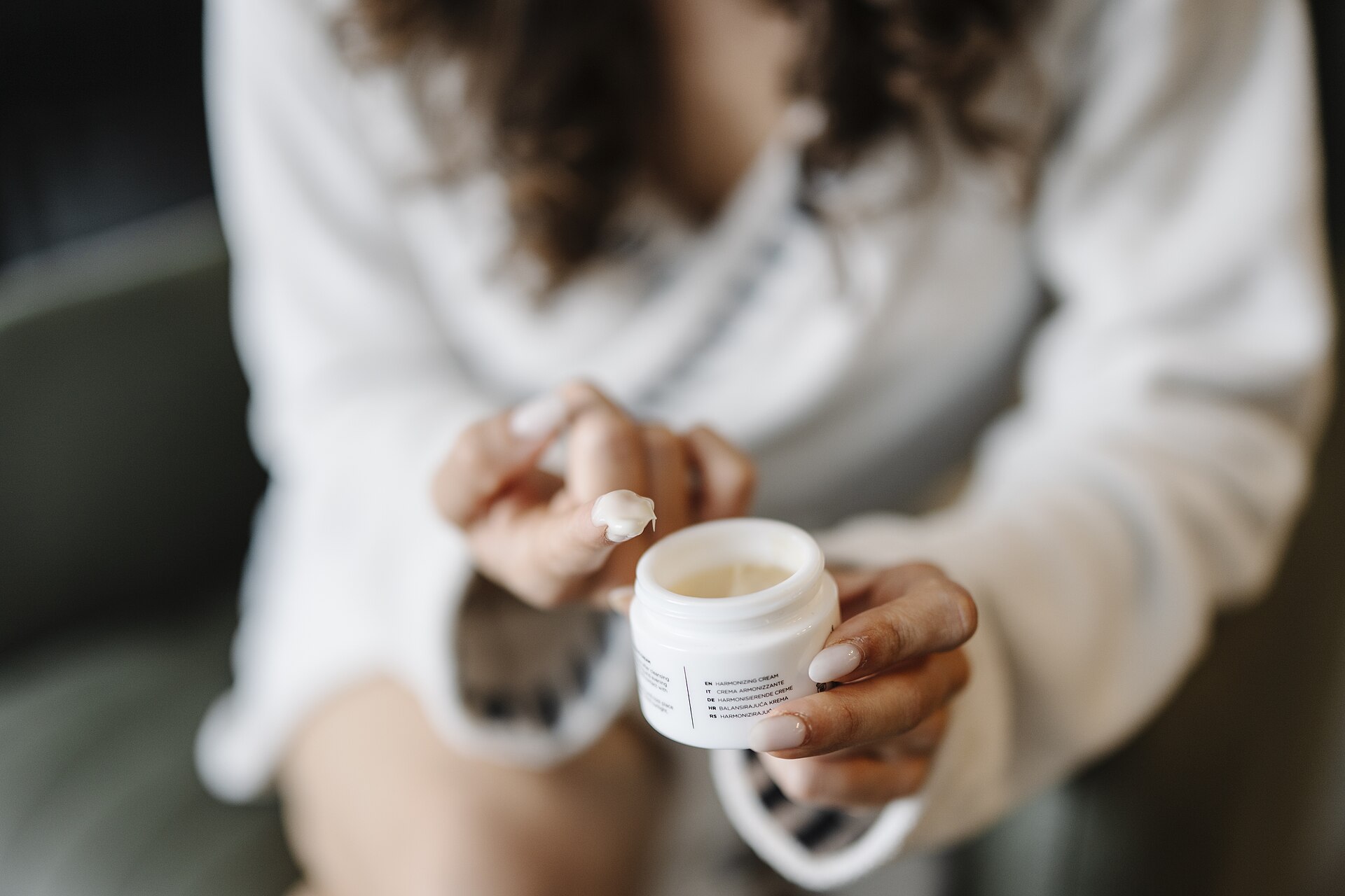 Mani che prelevano la crema da un vasetto